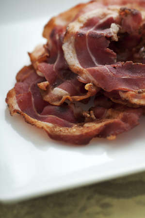 Freshly cooked heap of pancetta on white plateの写真素材