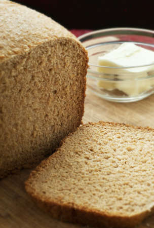 Whole wheat loaf of bread sliced with ramekin of butter