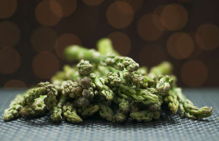 Pile of fresh asparagus on a mat with golden bokeh backgroundの写真素材