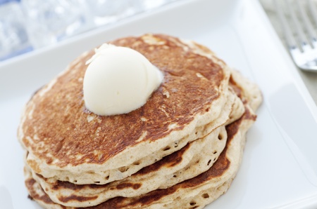 Fresh buttermilk pancakes with scoop of butter on white plateの写真素材