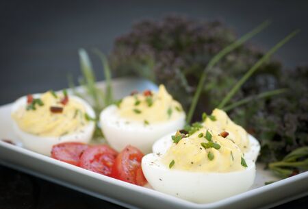 Decorative piped filling in deviled eggs with vegetable and herb garnishの写真素材