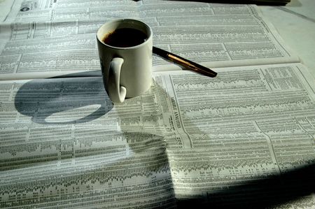 a tasty cup of coffee with the stock charts and a gold penの写真素材