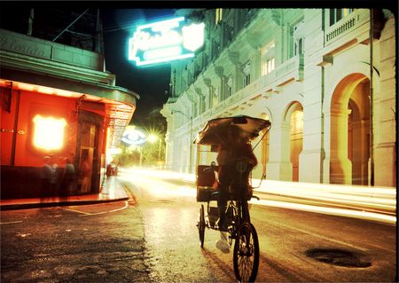 a vendor on a three wheel bike going past the famous floridita bar in old havana, cuba
