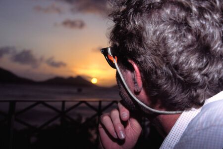 a man looking at the sunset over a caribbean islandの写真素材