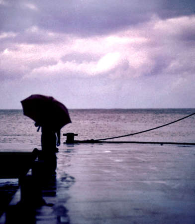 a dreamy shot of a person on a pier with an umbrellaの写真素材
