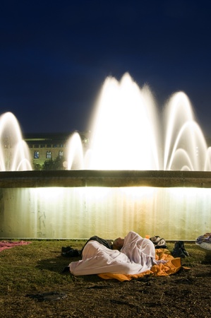 BARCELONA, SPAIN-MAY 29: Couple sleeping on ground outdoors by fountain in Plaï¿½a Catalunya the Square of Catalonia Plaza during The Assembly protest by workers and European young people taking over Catalonia Square in Barcelona beginning on May 15, 2011のeditorial素材