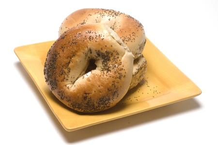 fresh baked poppy seed bagels on yellow plate の写真素材