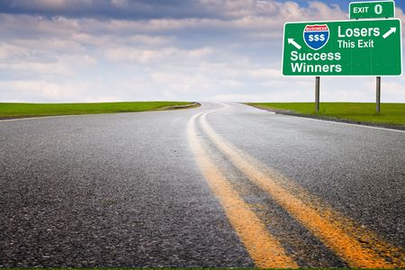 Asphalt pavement through green grass meadowの写真素材