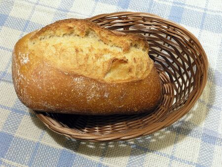 Fancy baked bread in a woven basket on a blue checkered cloth