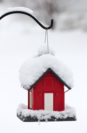 Hanging red snow covered bird feederの写真素材