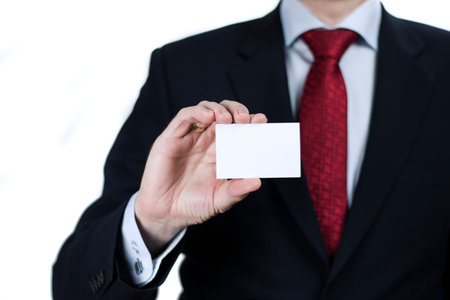 Close up of businessman wearing suit holding blank card on white backgroundの写真素材