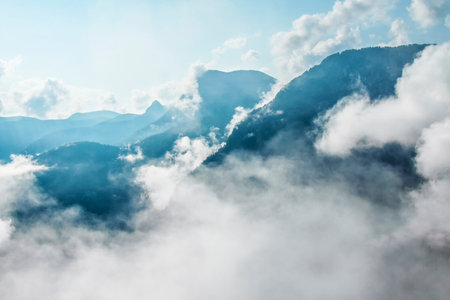 Photo of atmospheric blue misty mountains with clouds in the skyの写真素材