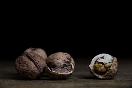 Close up of broken walnuts on rustic wooden board with black backgroundの写真素材