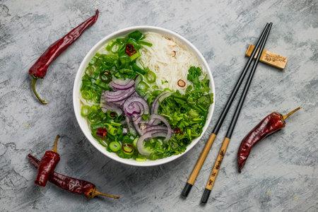 Served bowl of Vietnamese soup pho ga with spring onion, chili peppers and coriander on rustic backgroundの写真素材