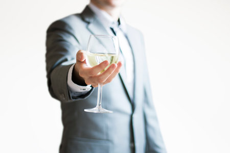 Photo of a businessman in a light gray suit holding a glass of white wine - celebrating successの写真素材