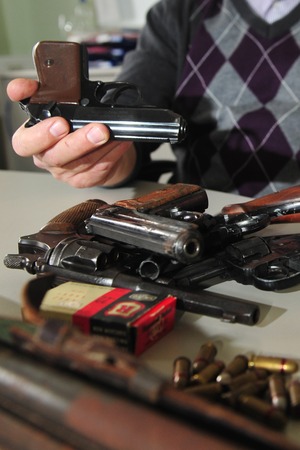Worms, Germany - November 26, 2009 - Officer shows guns and ammunition confiscated during a raid