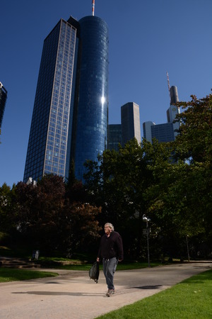 Frankfurt, Germany - October 1, 2015 - Main Tower and Commerzbank Tower seen from Taunusanlage with person walking byのeditorial素材