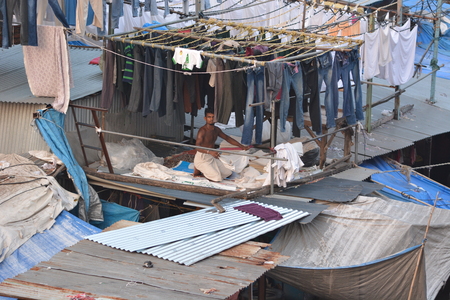 Mumbai, India - October 19, 2015 - Muslim washing spot Dhobi Ghat in front of Mumbai skyline. Man folding clothesのeditorial素材