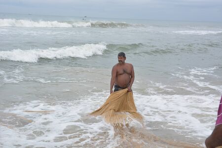 Goa, India - November 5, 2015 - Fishermen catching fishes the traditional way and repairing their huge netsのeditorial素材