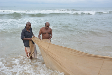 Goa, India - November 5, 2015 - Fishermen catching fishes the traditional way and repairing their huge netsのeditorial素材