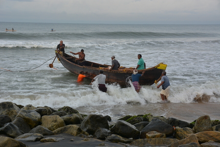 Goa, India - November 5, 2015 - Fishermen catching fishes the traditional way  sharing the catch and bargaining. Pushing their boat into the waterのeditorial素材