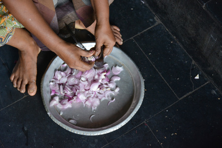 Mumbai, India - October 28, 2015 - Woman cutting chili and onions on a traditional cutting stool  in indian kitchenのeditorial素材