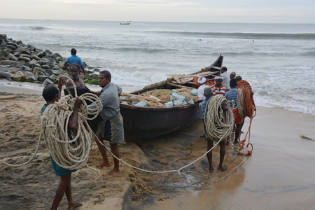 Goa, India - November 5, 2015 - Fishermen catching fishes the traditional way  sharing the catch and bargaining. Pushing their boat into the waterのeditorial素材
