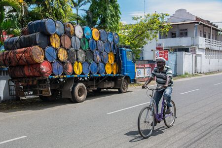 Mumbai, India - December 11, 2016 - Man cycling beside oil barrels