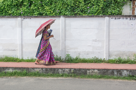 Mumbai, India - December 11, 2016 - Indian woman walking on street alone with umbrellaのeditorial素材