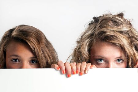 Two girls looking over white surfaceの写真素材