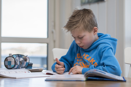 Boy writing and doing homework in the kitchen 