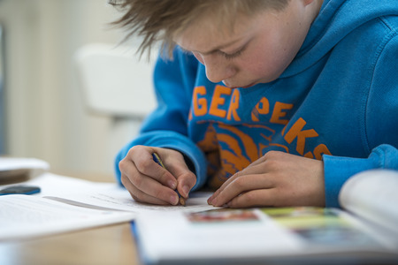 Boy writing and doing homework in the kitchen 