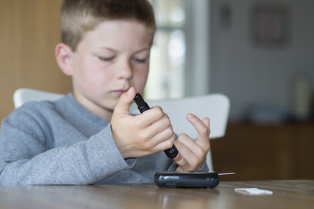 Young boy measure glucose level from a drop of blood.の写真素材
