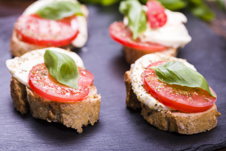 small sandwich with tomato and mozzarella, decorated with basil leafの写真素材