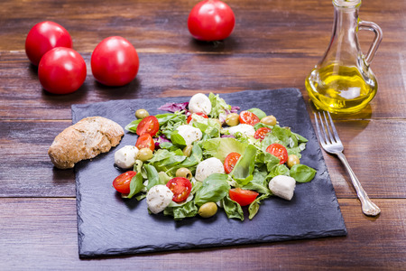 salad with mozzarella and tomatoes served on a stone plateの写真素材