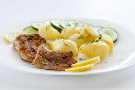 fish and potatoes on white plateの写真素材