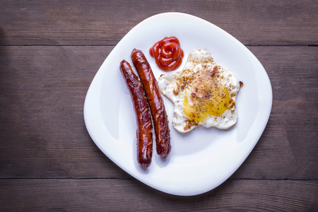 fried egg and sausages on white plateの写真素材