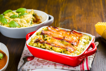 Baked pasta with spinach and olives in tomato sauce baconの写真素材