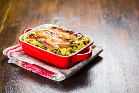 Baked pasta with spinach and olives in tomato sauce baconの写真素材