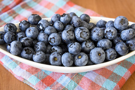 White bowl with blueberries on a wooden tableの写真素材