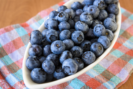 White bowl with blueberries on a wooden tableの写真素材