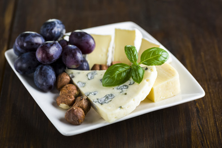 Appetizers - small plate of blue cheese, camembert cheese, grapes and walnutsの写真素材