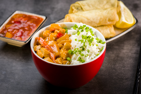 Chicken in sweet and sour sauce with rice and spring rollsの写真素材