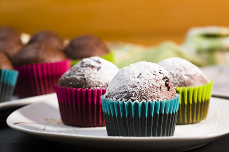 Chocolate muffins sprinkled with icing sugar on a white plateの写真素材