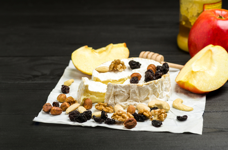 Camembert with nuts, fruit and honey on a wooden tableの写真素材