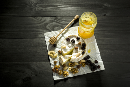 Camembert with nuts, fruit and honey on a wooden tableの写真素材