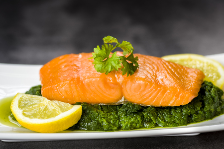 salmon on spinach decorated with parsley and lemonの写真素材