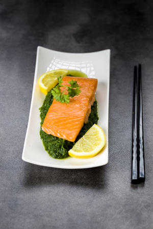 salmon on spinach decorated with parsley and lemonの写真素材