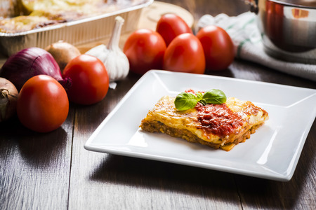 an appetizing portion of lasagna on a white plate topped with tomato sauceの写真素材
