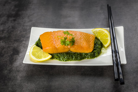 salmon on spinach decorated with parsley and lemonの写真素材